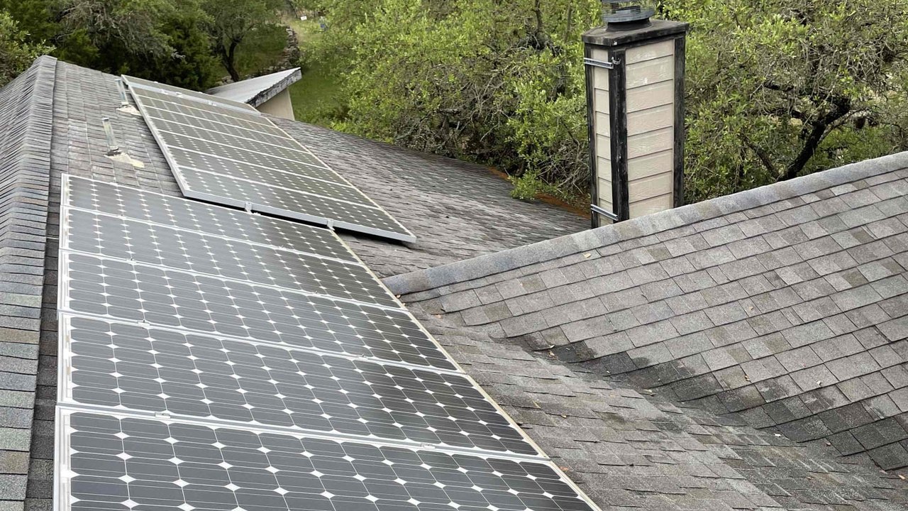 Original silver-framed solar panels on a shingle roof before the upgrade