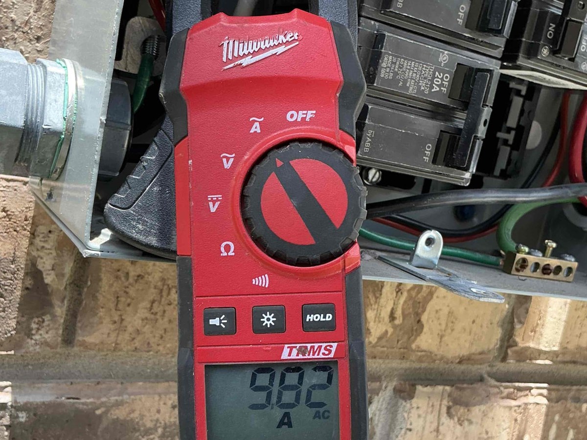 Clamp meter reading current at a solar AC disconnect during a home sale inspection