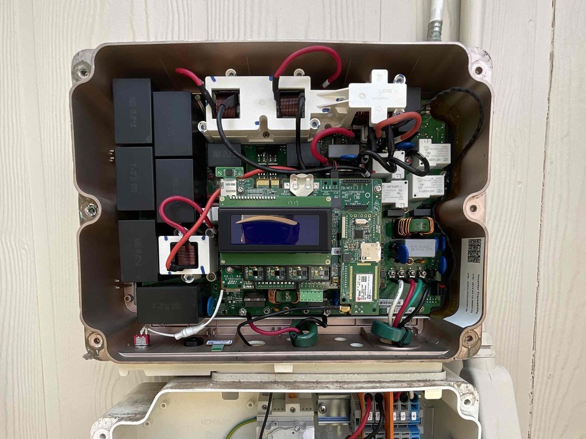 Inside an opened solar inverter showing the control board, relays and DC wiring during a repair