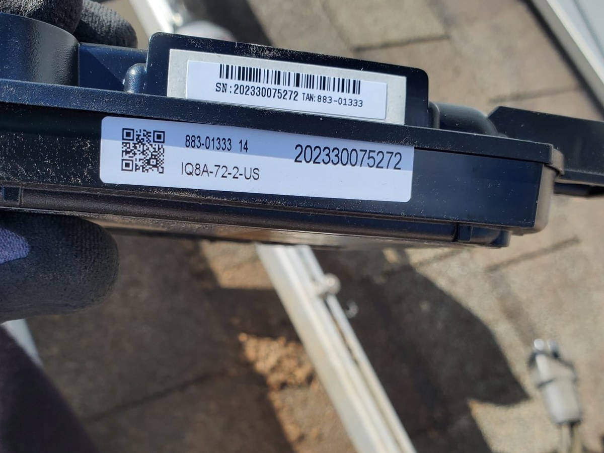 Enphase IQ8A microinverter mounted on a rooftop rail during a replacement