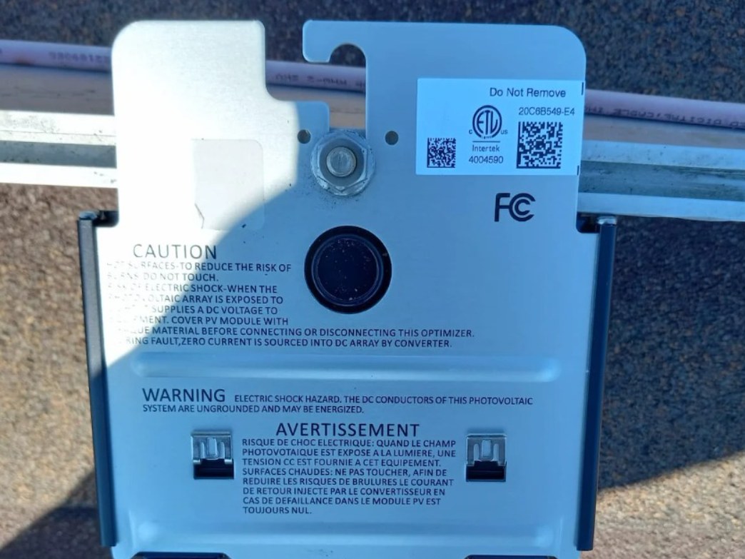 SolarEdge power optimizer mounted on the racking rail beneath a solar panel